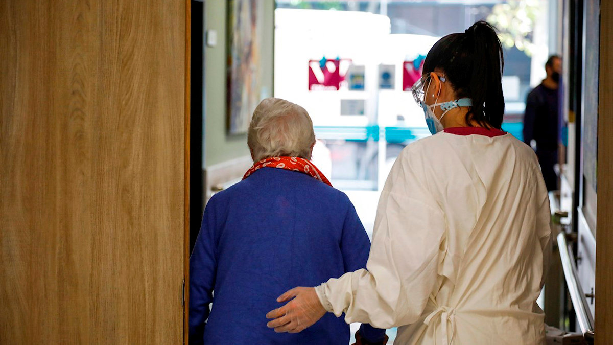 Una trabajadora de una residencia de mayores ayudando a una paciente. Foto: David Fernández / EFE