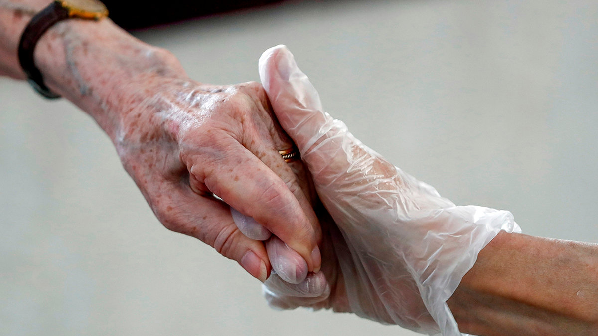 Residente y allegado dándose la mano durante una visita a un centro sociosanitario.— EFE