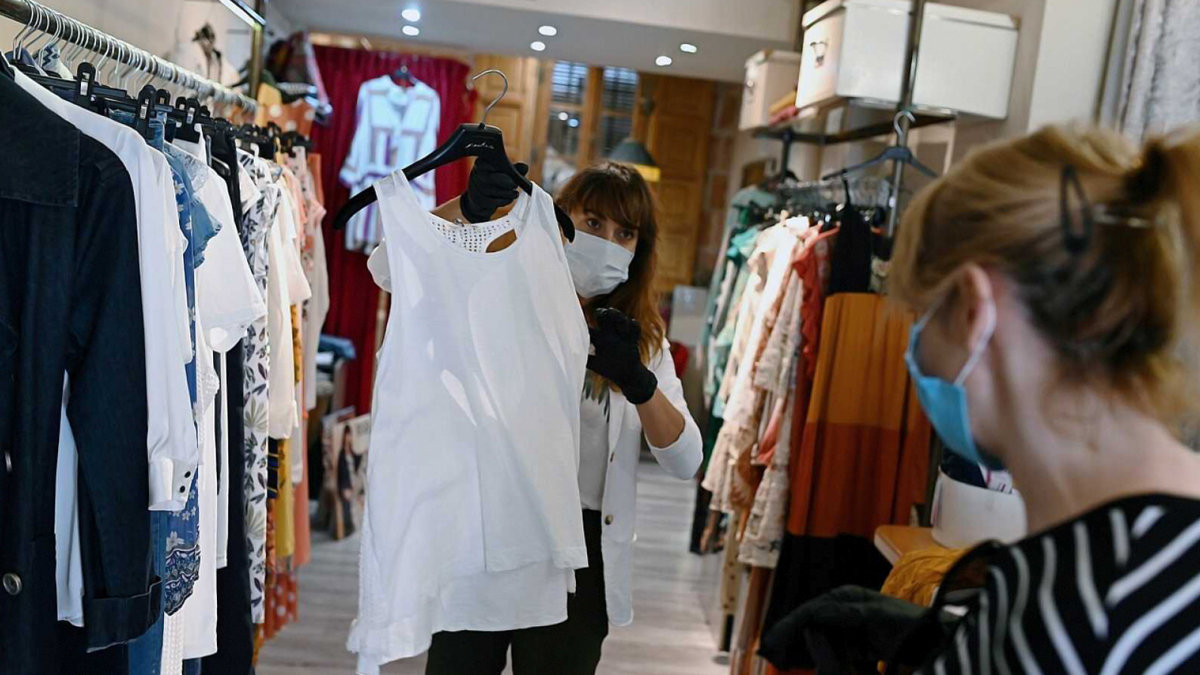 Una dependienta de una tienda de ropa muestra una prenda a una clienta.— EFE
