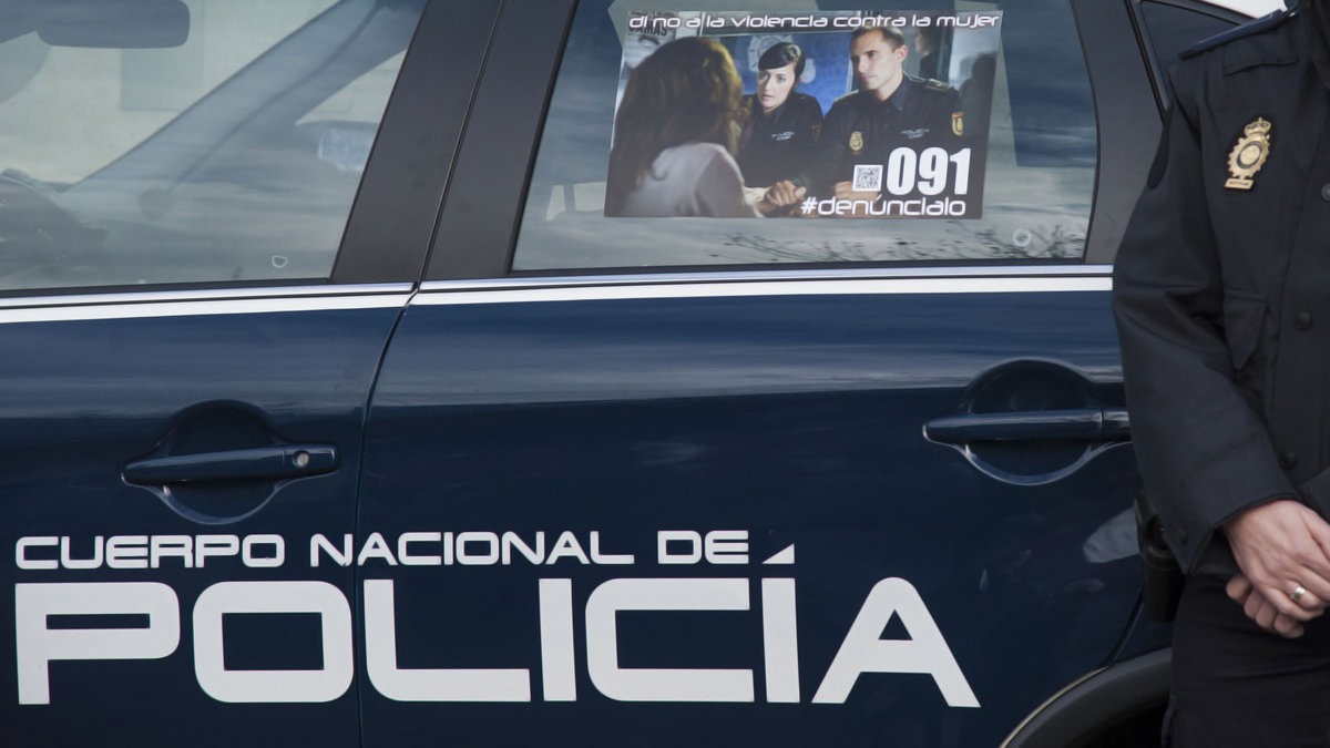 Agente de la Policía Nacional junto a un cartel del Cuerpo contra la violencia hacia la mujer. - ARCHIVO
